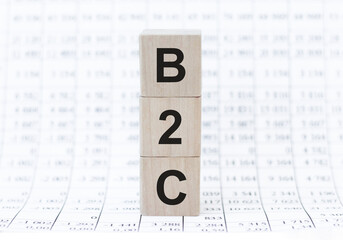 B2C letters of wooden blocks in pillar form on graph background, copy space