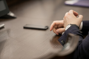 One of politician sitting by table with his hands over document during political summit or conference