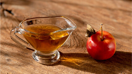 Apple cider vinegar in the glass and apple on a natural background.