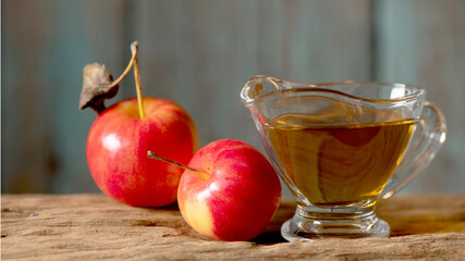 Apple cider vinegar in the glass and apple on a natural background.