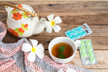 herbal healthy drinks hot tea and lozenge for health care sore throat with teapot ,flowers frangipani of lifestyle arrangement flat lay style on background wooden
