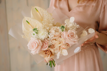 young woman florist in a pink dress with red hair holds a wedding bouquet of flowers roses