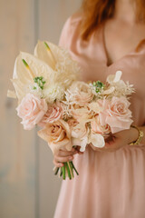 young woman florist in a pink dress with red hair holds a wedding bouquet of flowers roses