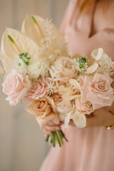 young woman florist in a pink dress with red hair holds a wedding bouquet of flowers roses