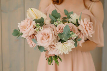 young woman florist in a pink dress with red hair holds a wedding bouquet of flowers roses
