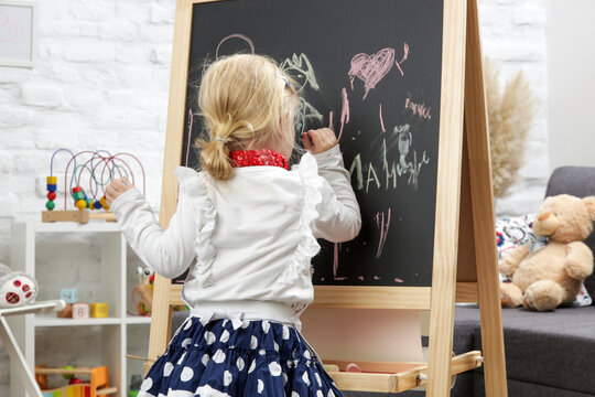 Indoor portrait of adorable 3 years old girl dressed up as a painter