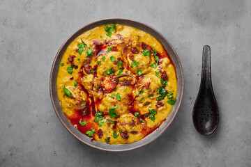 Punjabi Kadhi Pakora in gray bowl on concrete table top. Kadhi Pakoda is indian cuisine curry dish....