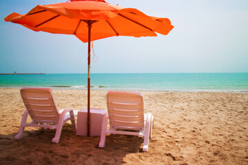 Orange umbrellas on white sandy beach along the beautiful sea in Cha Am, Thailand.