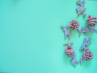 Christmas decoration made of wood for hanging at home during holidays. Xmas ornament with reindeer, pine cone and holly on green background. Copy space
