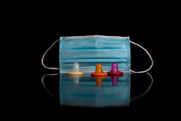 Bunte Kondome im Vordergrund und im Hintergrund eine Schutzemaske