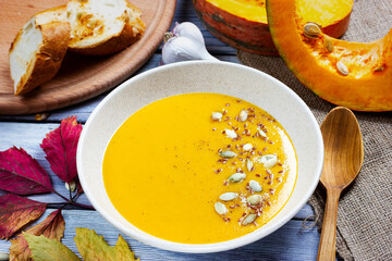 Autumn still life. Pumpkin cream soup with pumpkin seeds and pieces. Halloween theme