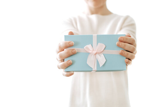 Gift in the hands of a woman. Close-up of female hands holding a blue gift wrapped in a pink ribbon.