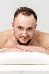 Obraz premium Young caucasian man lying on front on table spa, waiting for beauty treatment and looking at camera