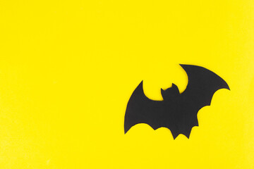 bat out of black paper on a yellow background, top view, background, Halloween
