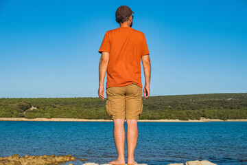 Man in short cargo pants observing the sea surface, Losinj island, Croatia