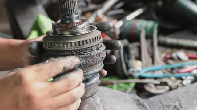 Hand of Car Mechanic or Auto Mechanic Removing Outer Drive Shaft Rubber Boot Band in Zoom View