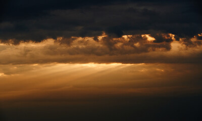 beautiful sunset sky, bright sun and dark silhouette of clouds as a background