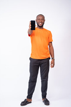 young african man smiling and showing his phone screen, standing against a white background