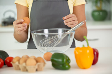 beautiful young woman cooking in kitchen break eggs in bowl