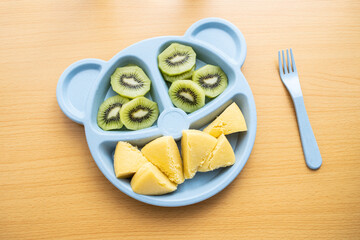 A plate of baby nutrition breakfast with millet cakes and kiwi