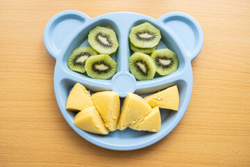 A plate of baby nutrition breakfast with millet cakes and kiwi