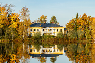 Fototapeta premium Kouvola, Finland - 2 October 2020: Autumn landscape with beautiful wooden Rabbelugn Manor - Takamaan Kartano. Wrede family house was built in 1820 on the river Kymijoki bank.