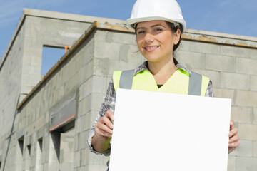 female worker wearing a hard hat holds a white banner