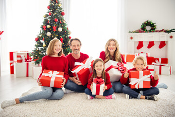 Obraz na płótnie Canvas Photo of full big family five people meeting three little kids sit carpet floor hold presents boy show thumb-up wear red jumper in living room x-mas tree garland gift boxes indoors