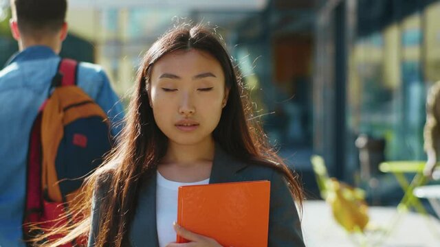 Portrait of lovely young asian student woman in sunny street. Beautiful nice-looking cheerful chinese girl outdoors. Modern youth. Urban lifestyle. University concept.