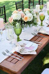 dinner tables with linen tablecloth, served with porcelain and green glasses. place cards for the...