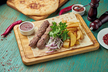 Classic Oriental grilled in bbq lula kebab with red sauce and side dish of baked potatoes. Eastern cuisine