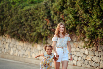 Mother and daughter walking in park during hot summer day. Family time outdoor.