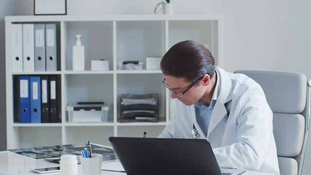 Professional medical doctor working in hospital office using computer technology.