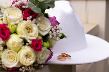 wedding rings on a white stylish hat next to the bride's bouquet. marriage concept.