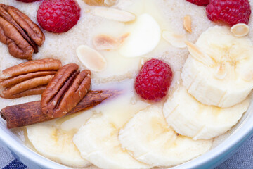 Delicious amaranth with butter, fresh raspberries and banana, pecans and almond chips. Plant-based breakfast. Healthy colorful gluten free concept.