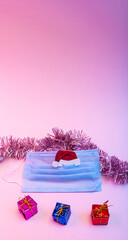 Coronavirus Christmas and New Year concept with medical mask, Santa's hat, christmas decoration, gift boxes in neon light. Copy space.