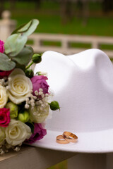 wedding rings on a white stylish hat next to the bride's bouquet. marriage concept.