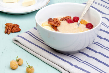 Delicious amaranth with butter, fresh raspberries and banana, pecans and almond chips. Plant-based breakfast. Healthy colorful gluten free concept.