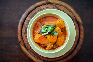 Chicken curry in a green bowl on a wooden base background.