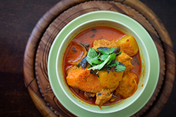 Chicken curry in a green bowl on a wooden base background.