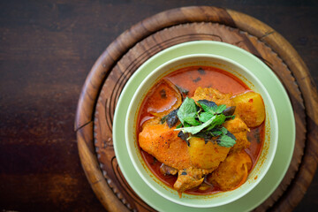 Chicken curry in a green bowl on a wooden base background.
