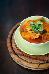 Chicken curry in a green bowl on a wooden base background.