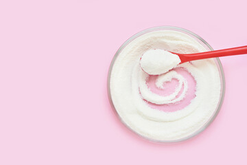 Collagen white powder. Pastel color background. Health product. Woman cosmetics concept. Sport supplement. Skincare cosmetics. Pink monochrome. Spoon