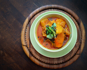 Chicken curry in a green bowl on a wooden base background.