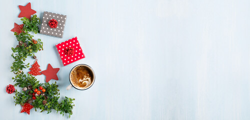 Rustic blue wooden background with cup of hot coffee, Christmas gifts and fir branches.