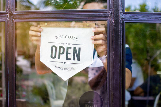 Staff held an opening sign on the front of the shop window to open the cafe in the morning