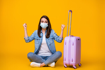 Portrait of her she nice attractive girl sitting crossed legs wearing safety mask waiting departure tourism boarding pass social distance isolated bright vivid shine vibrant yellow color background