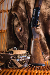 cartridge belt and 12 gauge hunting rifle in a rocking chair. the skin of a bear hangs on the back of a rocking chair