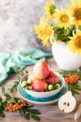 Autumn still life with pears and sunflower flowers on a wooden table