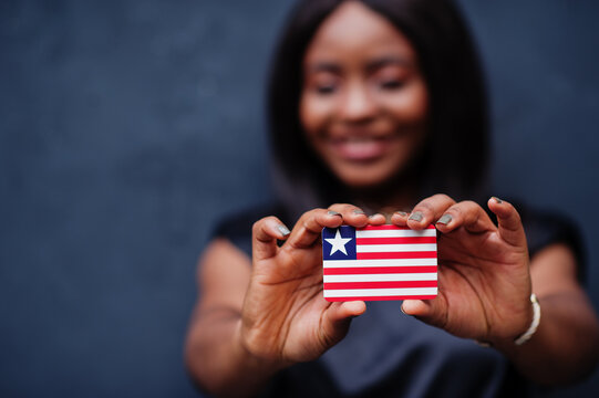 Proud to be liberian. African woman hold small Liberia flag in hands.